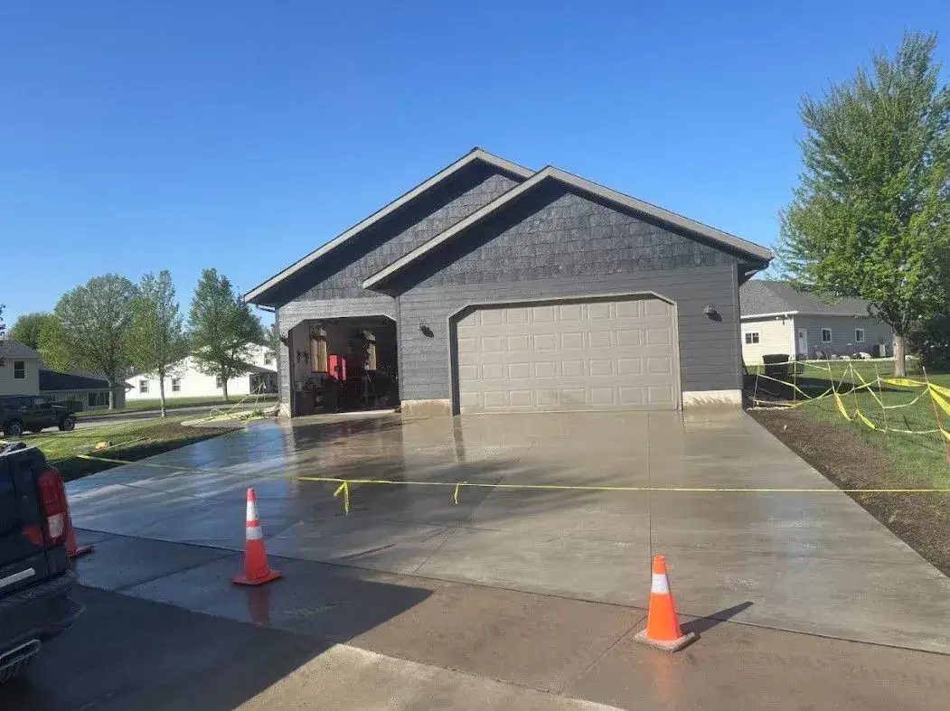 Freshly poured broom-finished concrete driveway in front of a two-car garage