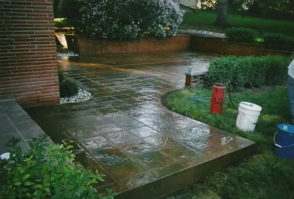 Stained and stamped concrete walkway beside a brick home